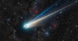 Межзвездная комета 3I/ATLAS летит на фоне далеких звезд со светящимся хвостом из плазмы.